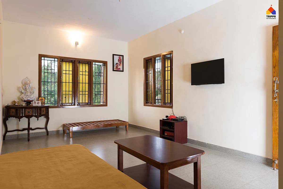 Common lounge with sofas and wooden tables at Trippr Kodaikanal