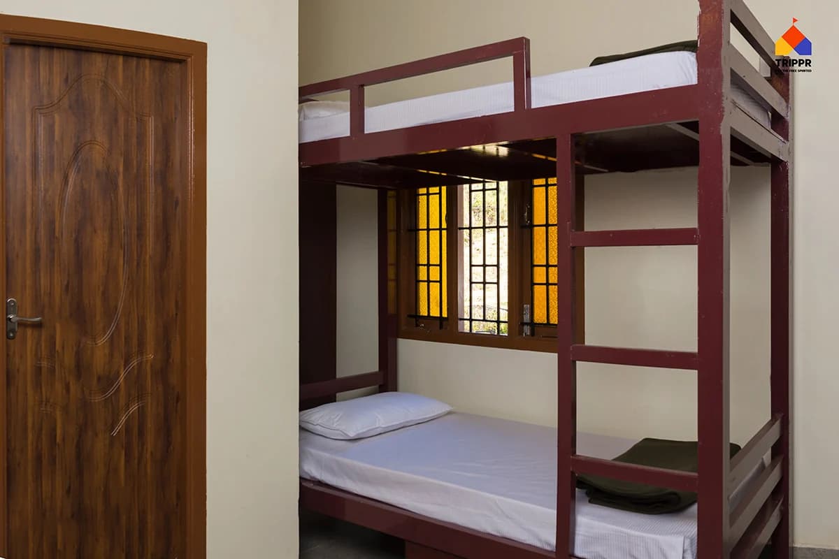 Wooden bunk beds beside a window at Trippr Kodaikanal
