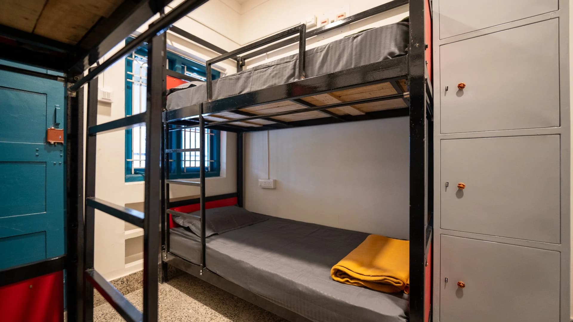 Bunk beds and teal doors in a Trippr Mysuru dormitory